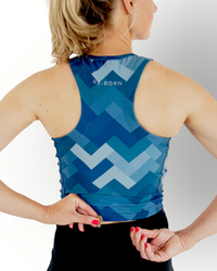 A woman wearing a sleeveless camo blue print sport crop top with matching double layered shorts.