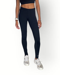 Person wearing black leggings and white sneakers on a white background