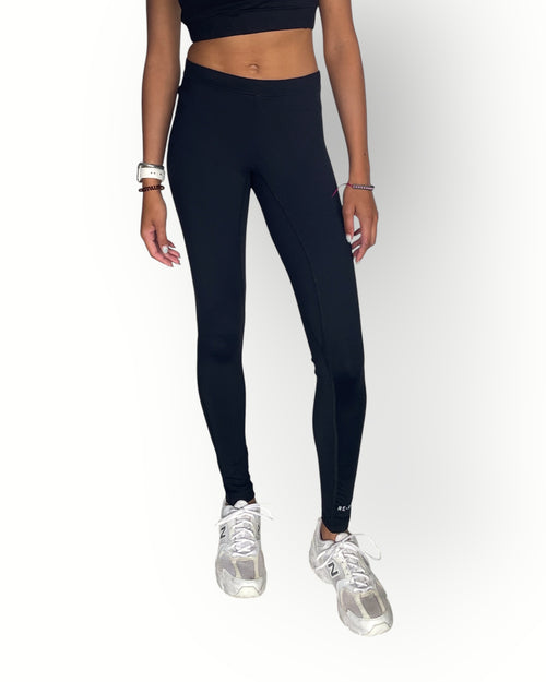 Person wearing black leggings and white sneakers on a white background