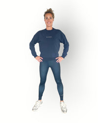 A woman wearing a navy long sleeve crew top with rib detail and a crew neckline in a super soft fabric and combined with the reversed sports legging in navy colour.