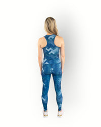 Woman wearing a blue geometric patterned sports tight that you can wear inside out. Model wears matching sport top.