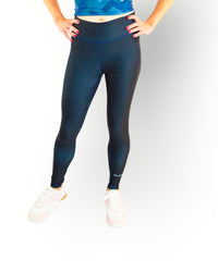 Woman wearing a Re-Born Sport Dames legging tight reversible navy with flat seams and pocket in waistband, you can wear the legging inside out. Models wears matching printed sport top.