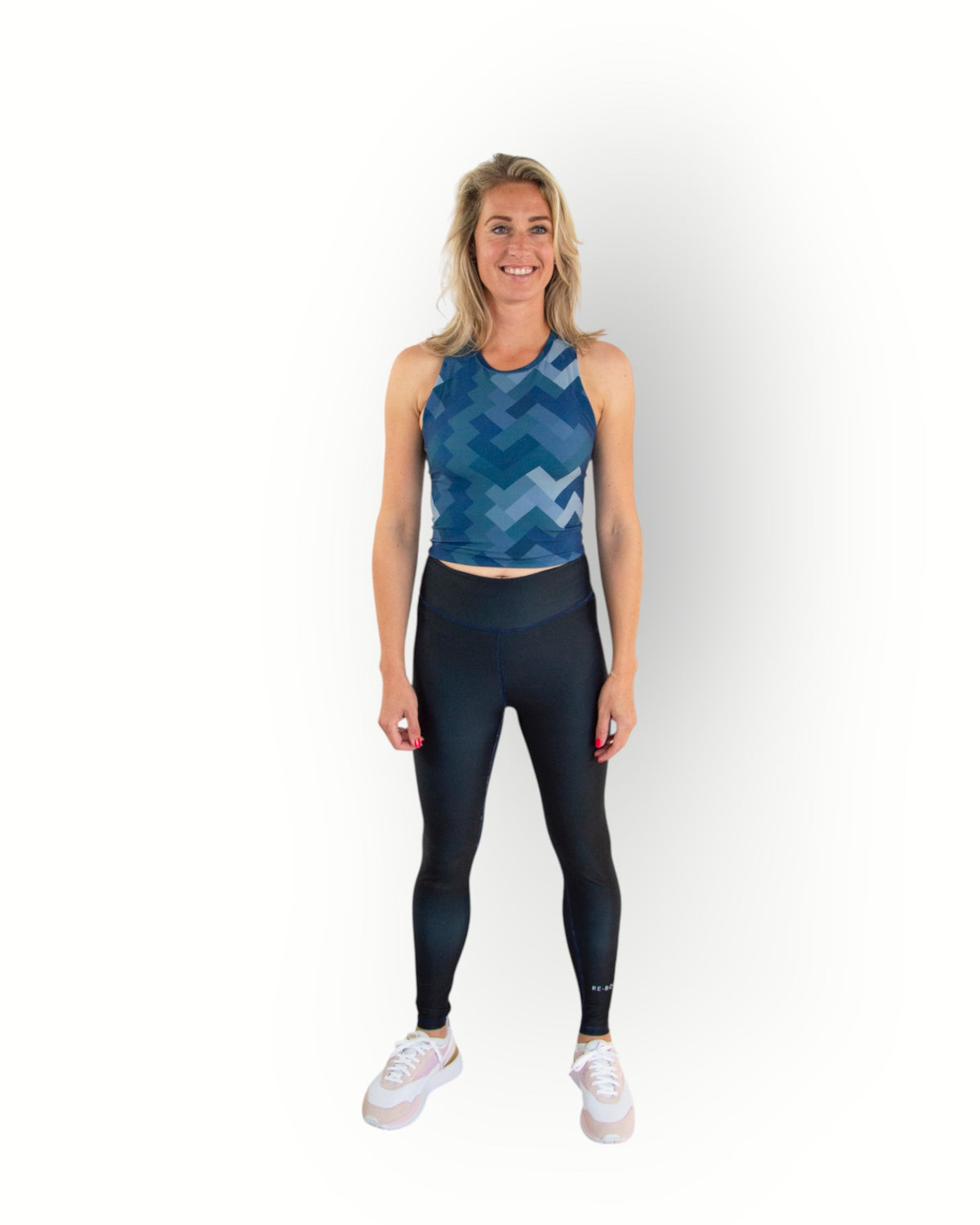 Woman wearing a Re-Born Sport Dames legging tight reversible navy with flat seams and pocket in waistband, you can wear the legging inside out. Models wears matching printed sport top.