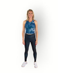 Woman wearing a Re-Born Sport Dames legging tight reversible navy with flat seams and pocket in waistband, you can wear the legging inside out. Models wears matching printed sport top.