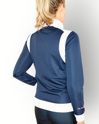 A woman wearing a navy and white color block training jacket with a full zipper and side pockets.