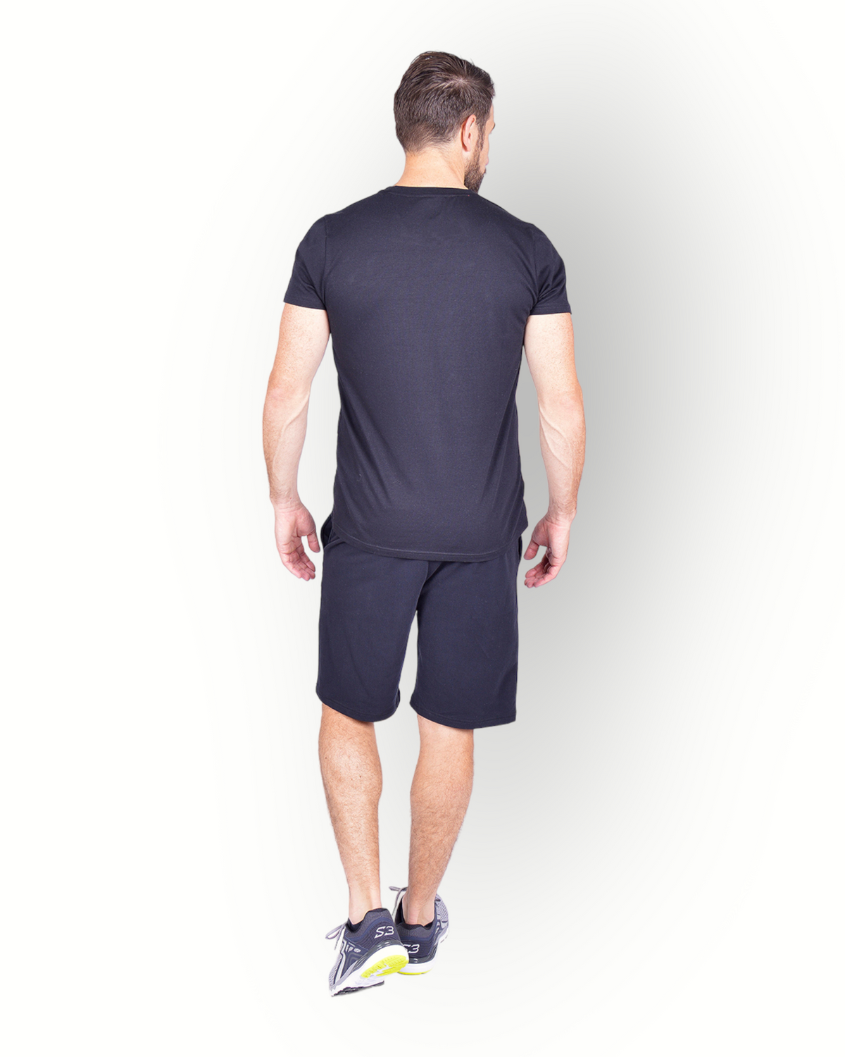 A man wearing a black short sleeve T-shirt with RE-BORN logo printed on the front combined with a black fleece shorts.