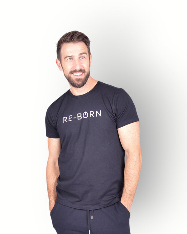 A man wearing a black short sleeve T-shirt with RE-BORN logo printed on the front combined with a black fleece shorts.