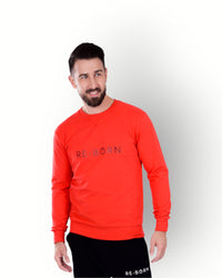 A man wearing a long sleeve red crew top with the brand name 'RE-BORN' on the front.