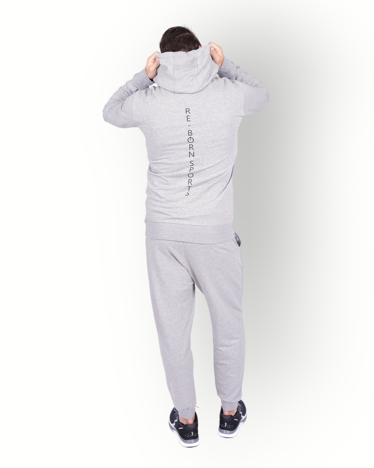 A man wearing a long sleeve full zip hooded top in grey, with side pockets and a scuba neck and printed E-BORN SPORTS on the back.