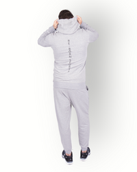 A man wearing a long sleeve full zip hooded top in grey, with side pockets and a scuba neck and printed E-BORN SPORTS on the back.