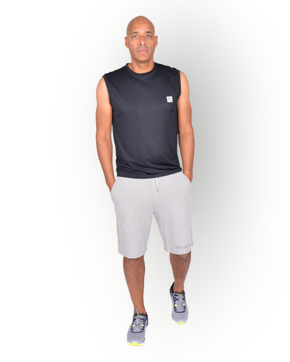 A man wearing a black sleeveless mesh light weight quick dry sport top with the text 'RE-BORN SPORTS' printed on the back, paired with gray shorts.