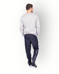 A male model wearing black poly side panel pants with white contrast with side pockets and zippers at the legs and a big RE-BORN logo at the back leg and combined with a grey sweater.