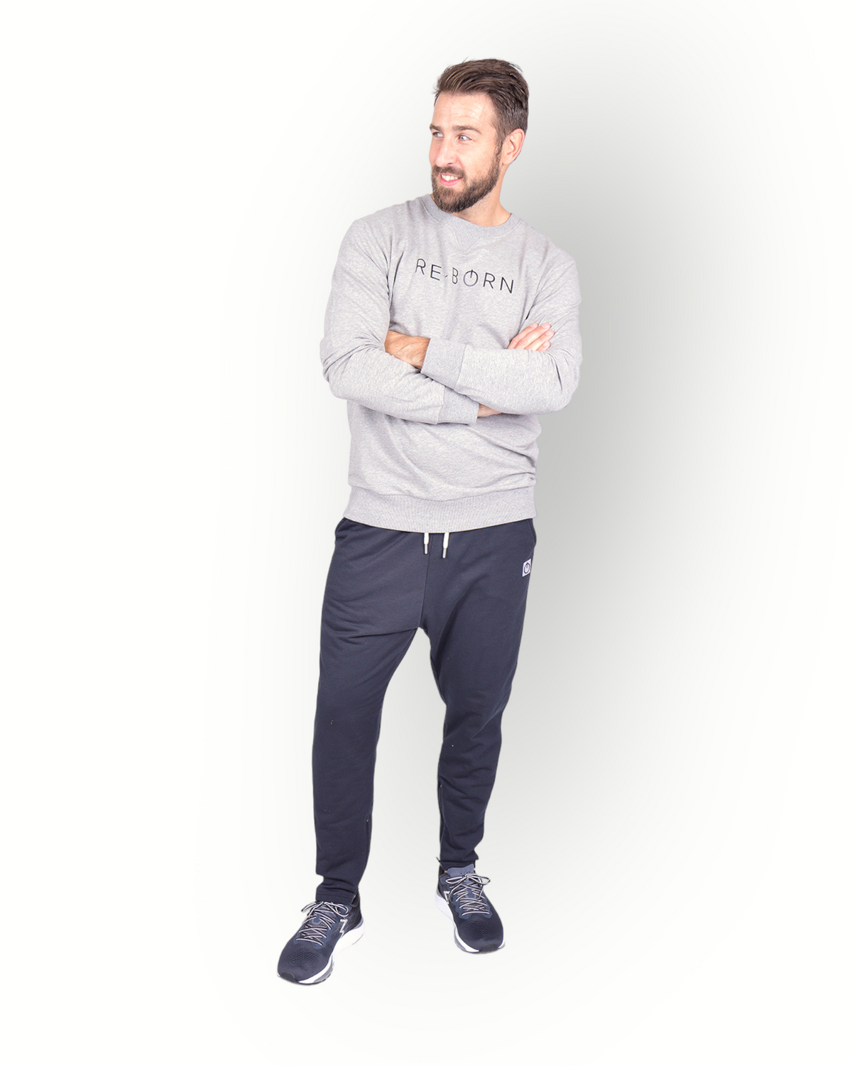 A male model wearing black poly side panel pants with white contrast with side pockets and zippers at the legs and combined with a grey sweater.
