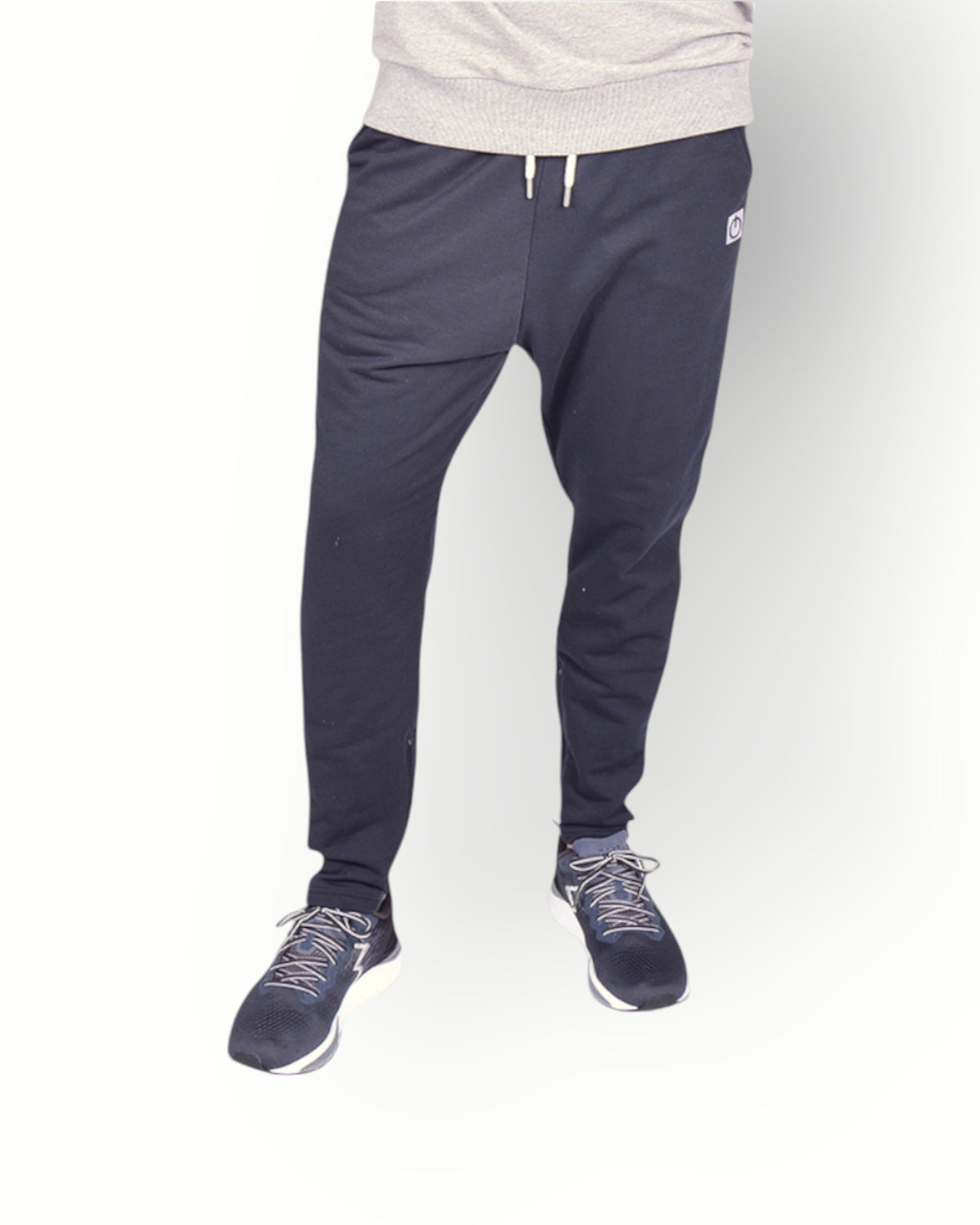 A male model wearing black poly side panel pants with white contrast with side pockets and zippers at the legs and combined with a grey sweater.
