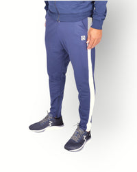A man wearing navy blue and white side panel pants with a logo on the back of the leg, paired with a navy full zipped hooded jacket.