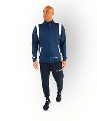 A man wearing a navy and white color block tracktop with a full zipper, high collar, and side pockets.