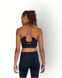 Person wearing a black long legging with zipper back pocket in waistband and sports bra with red and white striped back design 