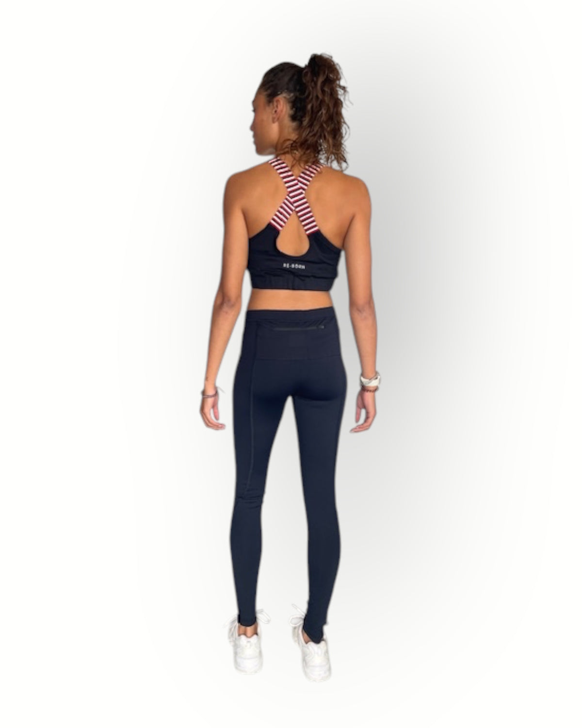 Person wearing a black sports bra and leggings set on a white background