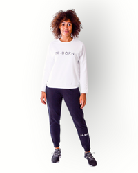 Woman wearing a white crew top with black RE-BORN logo printed on chest in super soft fabric.