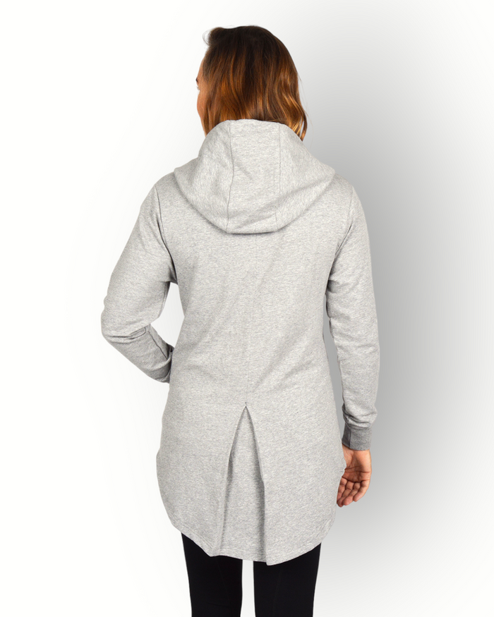 A woman facing away from the camera wearing a long sleeve grey full zip hoody with a hood and side pockets. and longer backside.