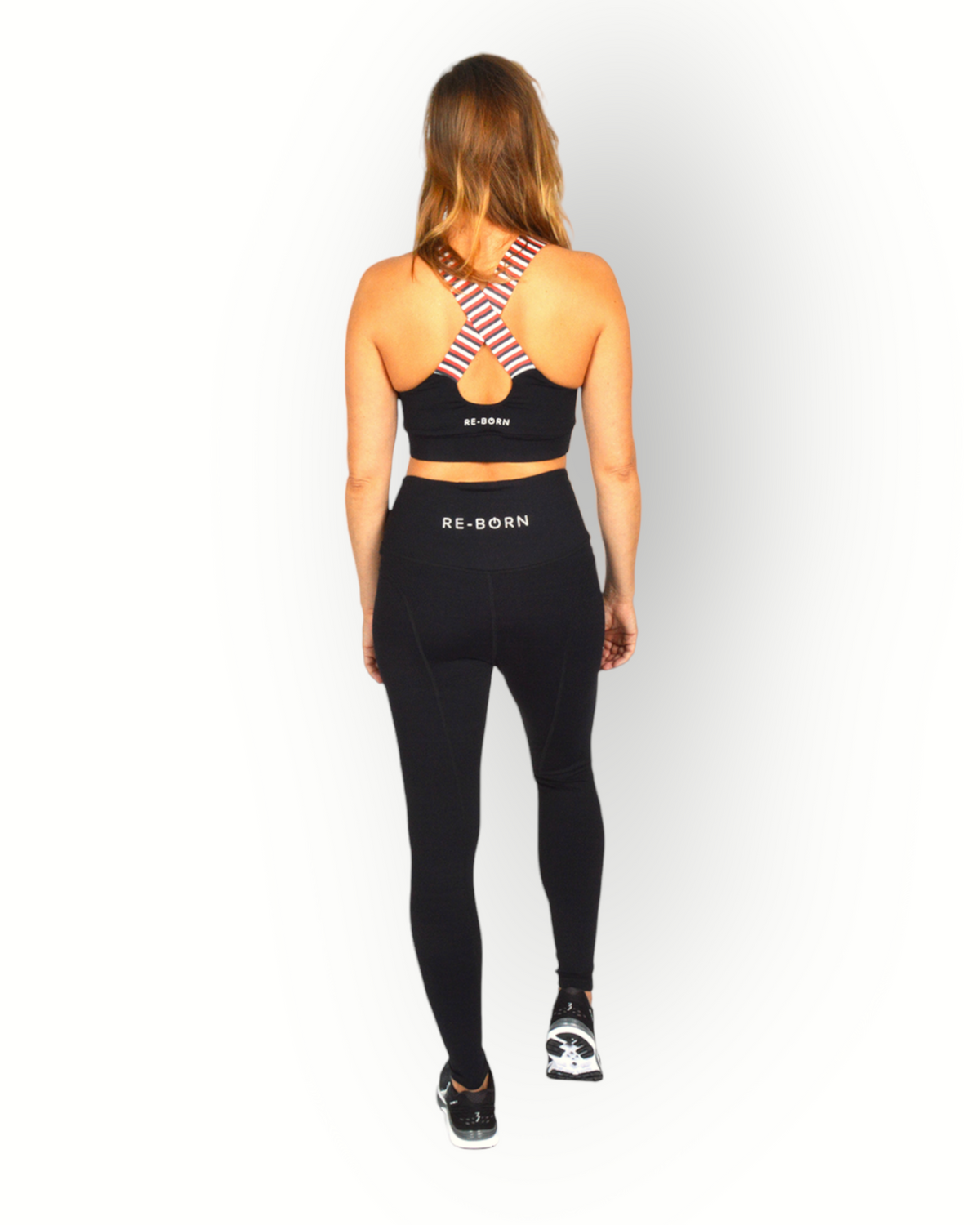 A woman standing and posing in a black sports bra with a cross-over elastic back, overlaid with a striped pattern on the elastic.