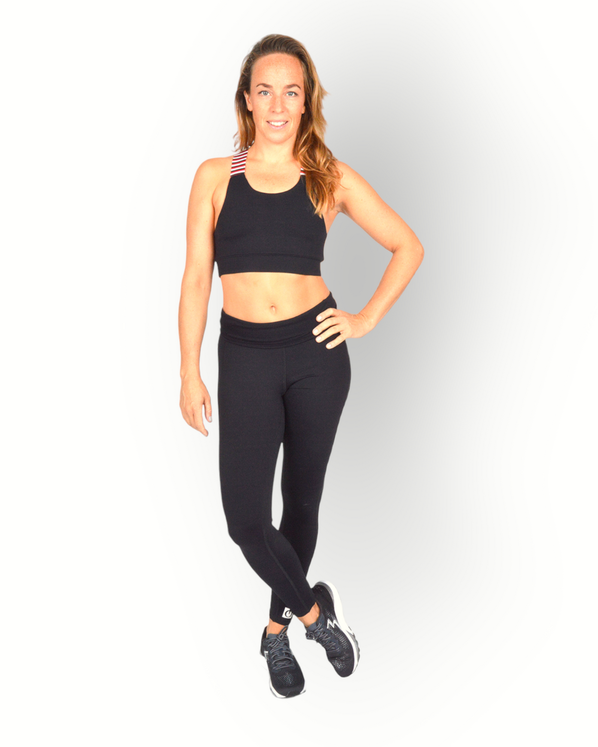A woman standing and posing in a black sports bra with a cross-over elastic back, overlaid with a striped pattern on the elastic.