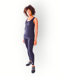 A woman wearing a black tank top with the brand name 'Re-Born' visible on the chest area, standing with hands on hips against a white background.