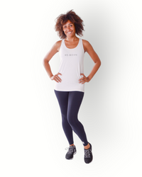 A woman wearing a white tank top with the brand name 'Re-Born' visible on the chest area, standing with hands on hips against a white background.