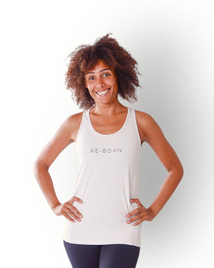A woman wearing a white tank top with the brand name 'Re-Born' visible on the chest area, standing with hands on hips against a white background.