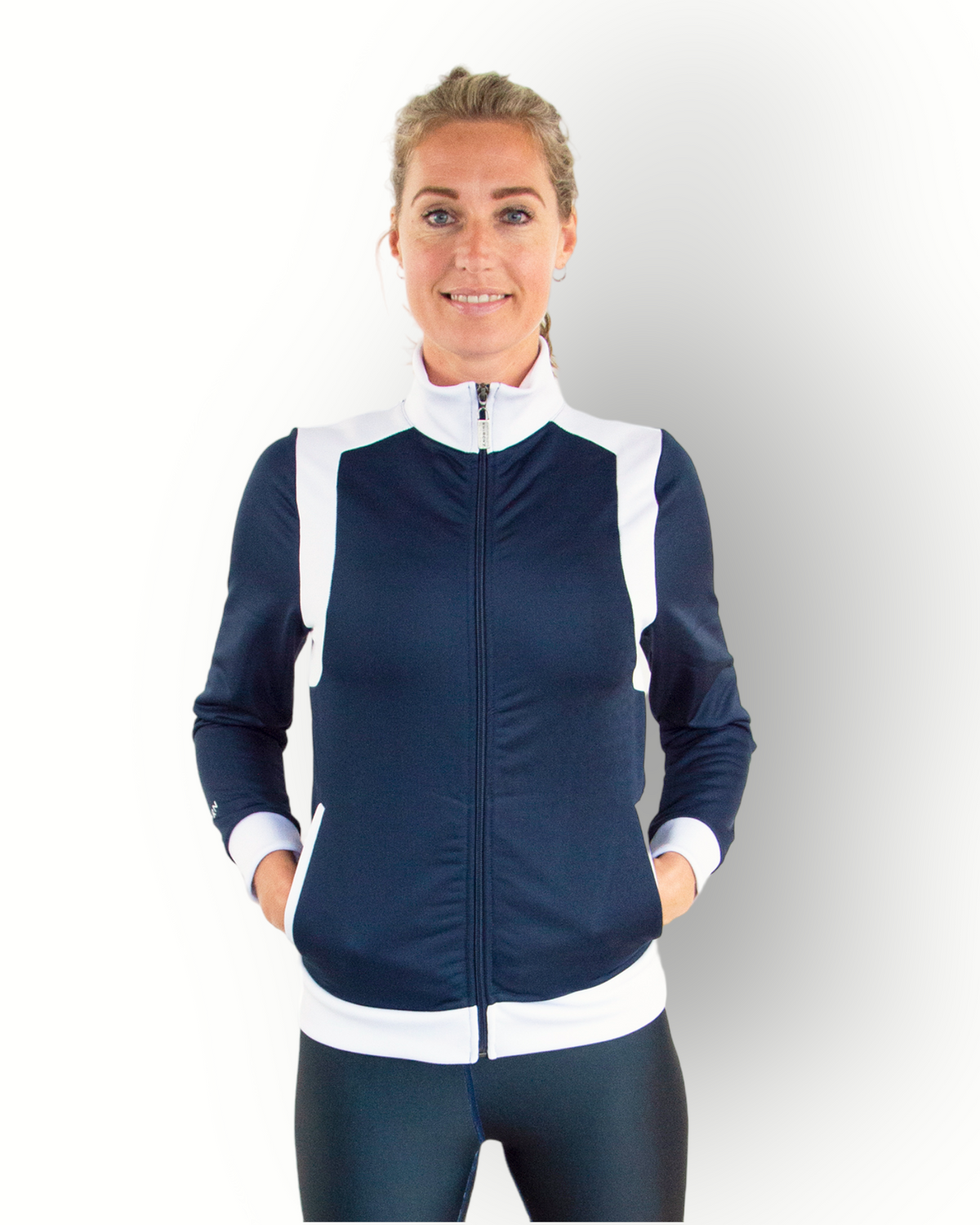 A woman wearing a navy and white color block training jacket with a full zipper and side pockets.