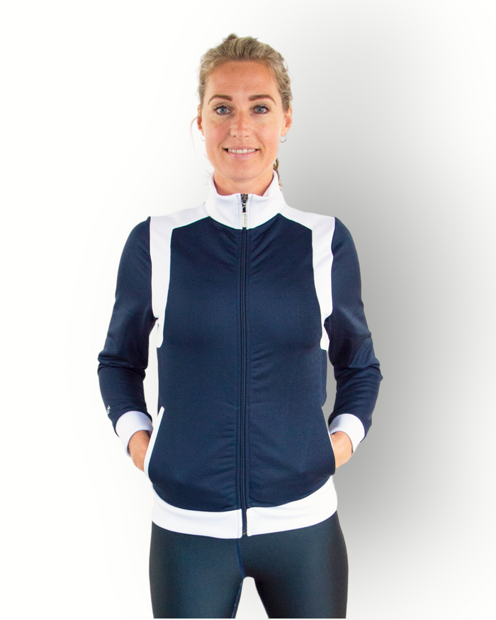 A woman wearing a navy and white color block training jacket with a full zipper and side pockets.