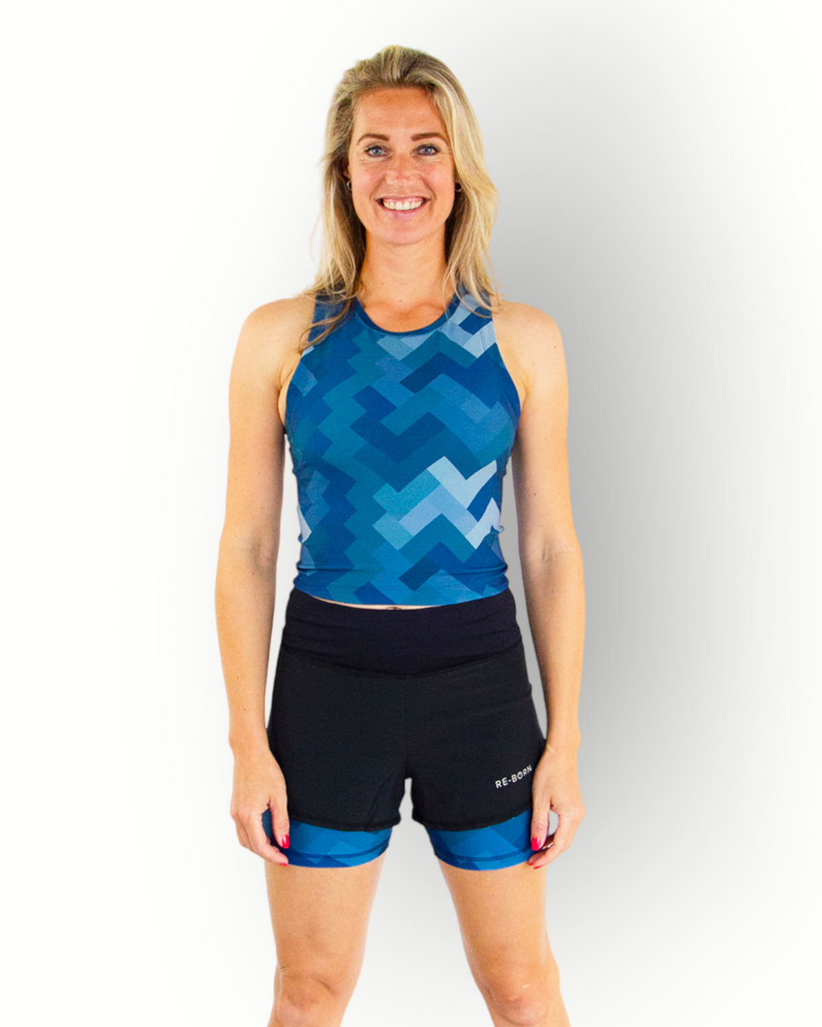 A woman wearing a black sports short with a camo blue print layer underneath. The short has an overlay fabric and an inner short, and there is a small pocket with zipper at the back inside the waistband.